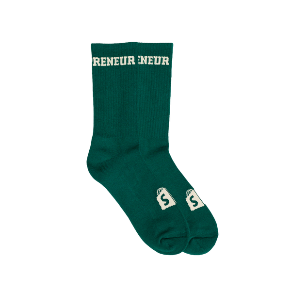 A pair of green & cream colored Shopify Supply Business as Usual Socks with a cream Shopify logo on the top of the foot.
